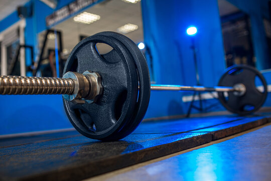 10 kg weight plate on barbell close up in gym, fitness training equipment with shallow depth of field