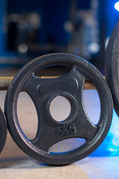 Black weight plate 2.5 kg on barbell close up in gym, strength training equipment detail