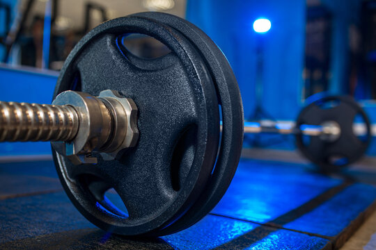 Barbell with weight plates on gym floor low angle perspective, strength training concept