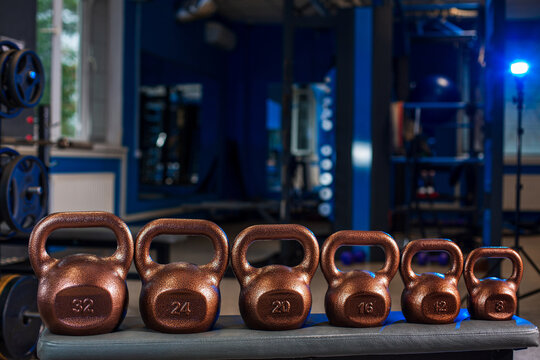 Close up of loaded barbell plates on gym floor with dramatic blue lighting, strength training concept