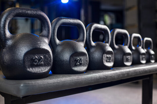 Group of kettlebells of different sizes on platform in gym, strength training equipment