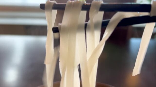 Eating ramen noodles pho bo dish at vietnamese restaurant with chopsticks
