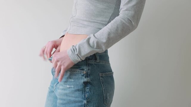 Woman fastening jeans after weight loss, body transformation and healthy lifestyle concept