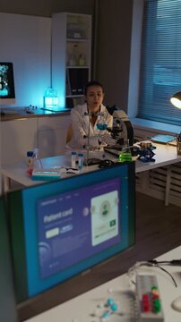 Vertical shot of bicultural young medical specialists analyzing patients card on computer while working in modern clinical laboratory