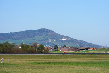 Obraz premium Scenic landscape with runway 16 of Zürich Airport with small town of Regensberg in the background on a sunny spring day. Photo taken April 8th, 2026, Zurich Airport, Switzerland.