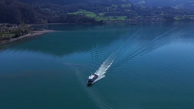 Passenger ferry approaching and passing by on a calm alpine lake in Switzerland, featuring outdoor seating deck and scenic mountain surroundings