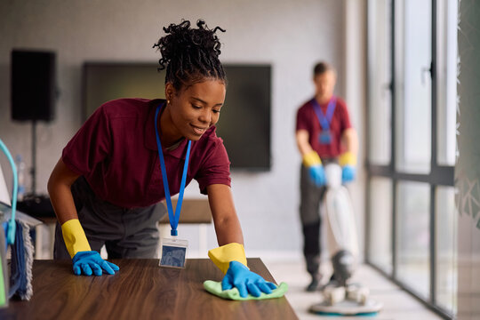 Black female cleaning technician maintaining cleanliness of office building.