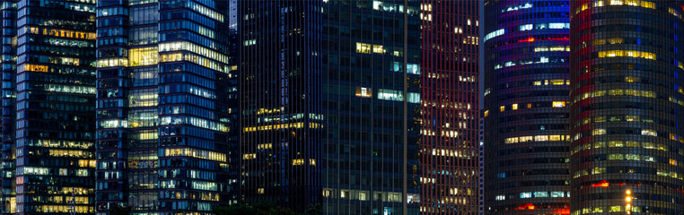 Obraz premium Multi-stories office building at night with worker working overtime. late night at office. lighting and working people within