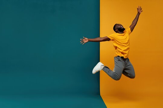 Man jumping with arms outstretched in color block studio