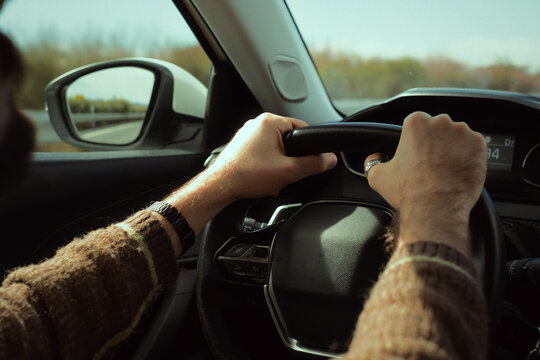 Man driving car on highway, hands gripping steering wheel, traveling and commuting with vehicle