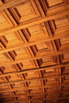 Wooden coffered ceiling showing geometric square panels, creating a textured pattern and enhancing architectural details
