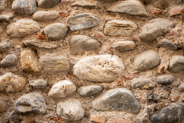 Ancient stone wall showing weathered masonry texture with natural river stones and rough mortar patterns © Sunlight