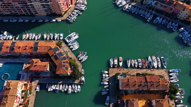 Sea-green water sparkles in the sun in the canals of marina. Many boats are at the berths of Port Saplaya, Valencia, Spain.