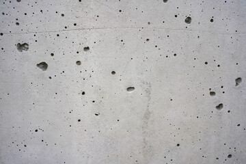 Grey concrete wall texture with porous holes and industrial weathered surface background