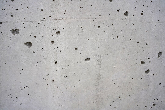 Grey concrete wall texture with porous holes and industrial weathered surface background