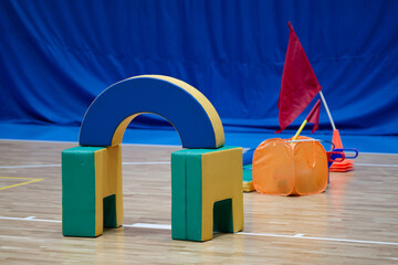 Obraz premium Soft foam sports equipment for kids obstacle course on an indoor gym floor. Training inventory for school physical education lessons, relay competitions and family sport activities. Photo