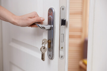 Naklejka premium Woman opening door with keys indoors, closeup