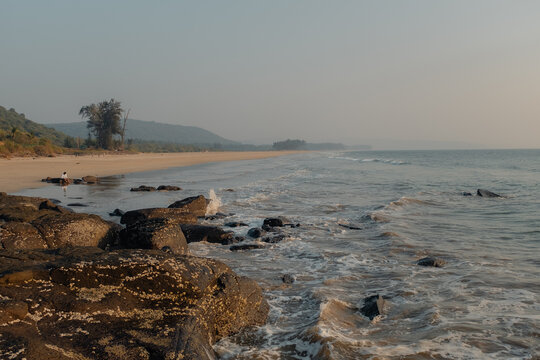 View of the sun-kissed beach where the sea whispers secrets to the weathered rocks, inviting a serene escape along the coast, Chiplun, Maharashtra, India.