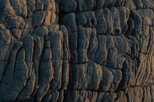 View of sun-kissed, rugged rock formations reveal intricate textures and shadows, creating a natural sculpture, Chiplun, Maharashtra, India.