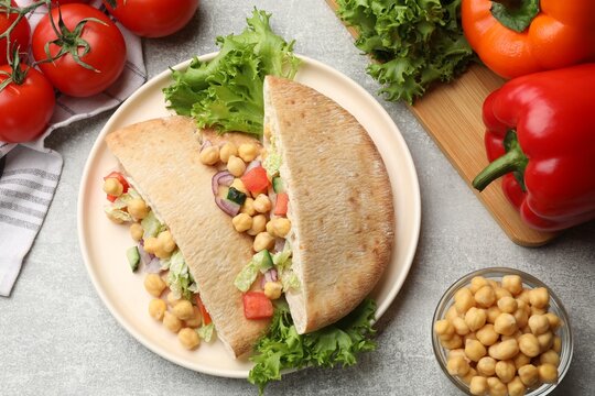 Pieces of pita bread with chickpeas and vegetables served on light grey table, flat lay