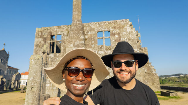 Multicultural Couple Wearing Hats Taking a Selfie in the Historic Center of Barcelos, Portugal
