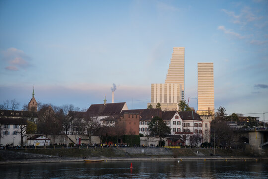 Basel, Switzerland - 10 March 2025: View of the towering Messe Basel skyscrapers, juxtaposed against the quaint old town architecture, reflecting in the tranquil waters.