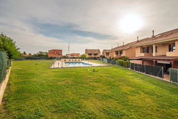 Obraz premium Irregularly shaped pool with a central island and artificial palm trees, surrounded by concrete planters with bougainvillea and modern-style lampposts