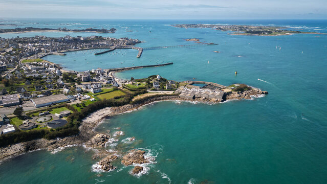 Aerial view of the rocky coastline embracing turquoise waters near the port and Ile de Batz, a dance of land and sea, Roscoff, Brittany, France.