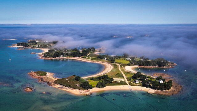 Aerial view of Ile Callot shrouded in ethereal mist, a tapestry of emerald islets fringed by azure waters, Carantec, Brittany, France.