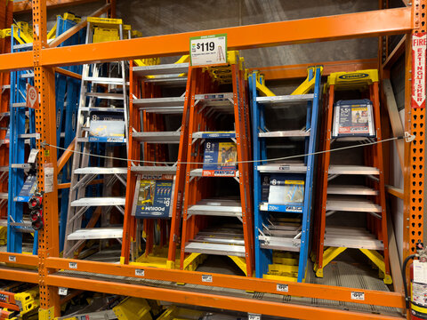 Prosper, Texas, USA - April 1st, 2026: Werner fiberglass step ladders in orange blue and silver colors standing on metal display shelves in The Home Depot