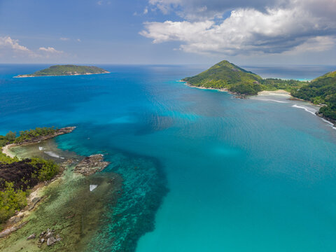 Aerial view of turquoise waters meet verdant islands under a vast sky, showcasing the natural beauty of the Seychelles, Victoria, Mahe Island, Seychelles.