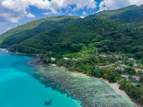 Aerial view of turquoise waters meet lush green hillsides by the coast, a tropical paradise of vibrant colors and serene beauty, Victoria, Mahe Island, Seychelles.