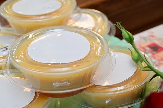 individual caramel flan portions in plastic cups, traditional brazilian pudim de leite condenseado for party, sweet custard dessert with caramel sauce in takeout packaging, group of mini flans 