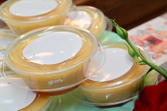 individual caramel flan portions in plastic cups, traditional brazilian pudim de leite condenseado for party, sweet custard dessert with caramel sauce in takeout packaging, group of mini flans 