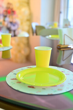 yellow disposable plate and cup for themed party, kids birthday table setting with neon green tableware, close up of party supplies and place mat, vibrant table decoration for children celebration