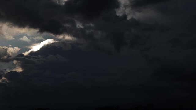 Dramatic dark clouds with bright sunlight breaking through.time lapse