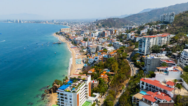 Aerial view of the vibrant coastline where the city meets the sea, a tapestry of buildings cascading down to the sandy beaches, Puerto Vallarta, Jalisco, Mexico.