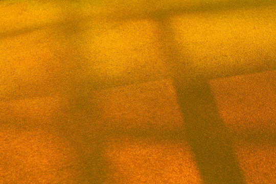 View of geometric shadows cast in warm hues across a textured ground, creating a mesmerizing dance of light and form, La Defense, Flevoland, Netherlands.