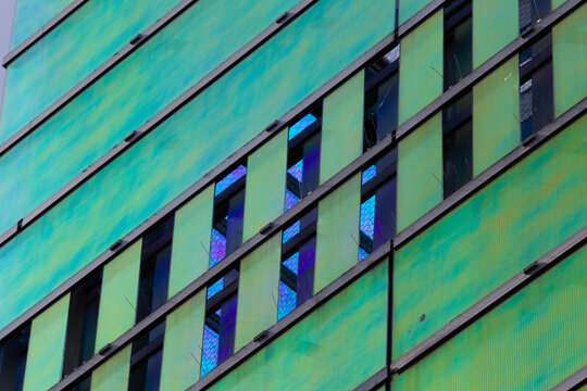 View of the building's facade displaying vibrant green panels complemented by the cool, dark reflections of the windows, La Defense, Flevoland, Netherlands.