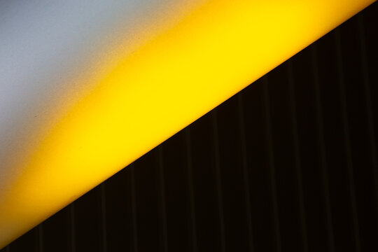 View of a stark contrast where bright yellow light dramatically intersects with a deep black textured surface and a soft grey area, La Defense, Flevoland, Netherlands.