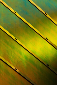 View of a striking architectural facade with diagonal bands of gold against a shimmering, iridescent green and bronze surface, La Defense, Flevoland, Netherlands.
