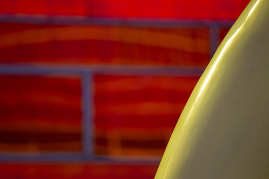 View of a yellow object contrasts against a vibrant red brick wall with blurred blue grout, creating a striking abstract composition, La Defense, Netherlands.