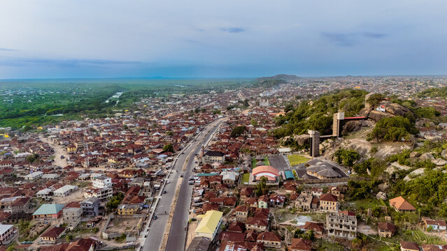 Aerial view of rooftops and a sprawling city blending into the horizon, with a prominent rock formation rising above the landscape, Ibadan, Nigeria.