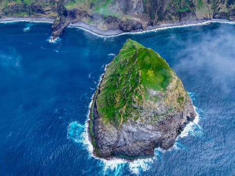 Aerial view of the verdant islet of Monchique dramatically contrasts with the deep blue sea, a testament to nature's artistry, Flores, Acores, Portugal.