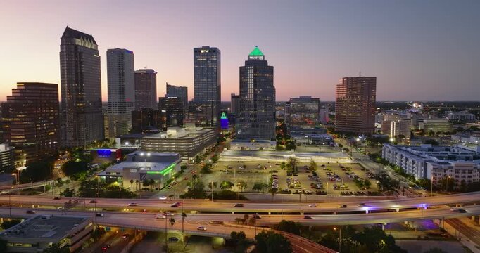 Tampa, Florida. Cars traffic driving on wide highway and high skyscraper buildings in downtown district. American city with business financial district at nightfall.