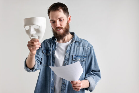 Professional actor with mask and script performing on light grey background