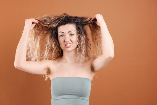 Unhappy woman with tangled hair on brown background