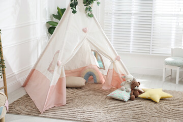 Toy wigwam with pillows, furniture and floral decor in room © New Africa
