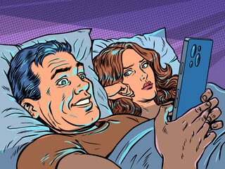 Pop Art Retro A man in bed with his wife looking at his phone. Relationship problems in a married couple. Infidelity and partner addiction. © studiostoks