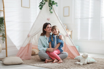 Mother and her daughter near toy wigwam at home © New Africa